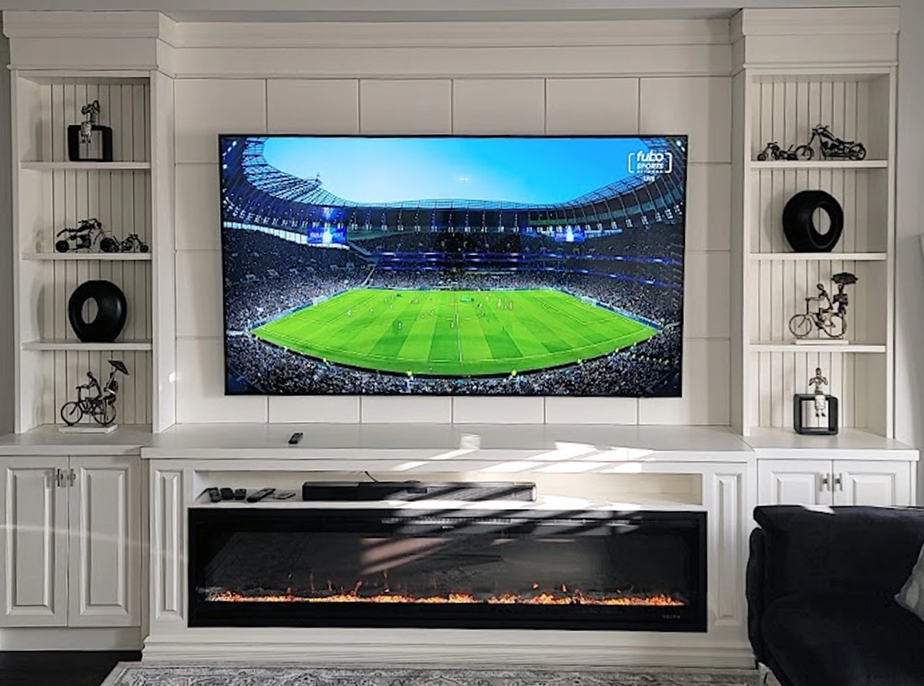 Custom white entertainment wall with open shelving, raised panel cabinetry and linear electric fireplace
