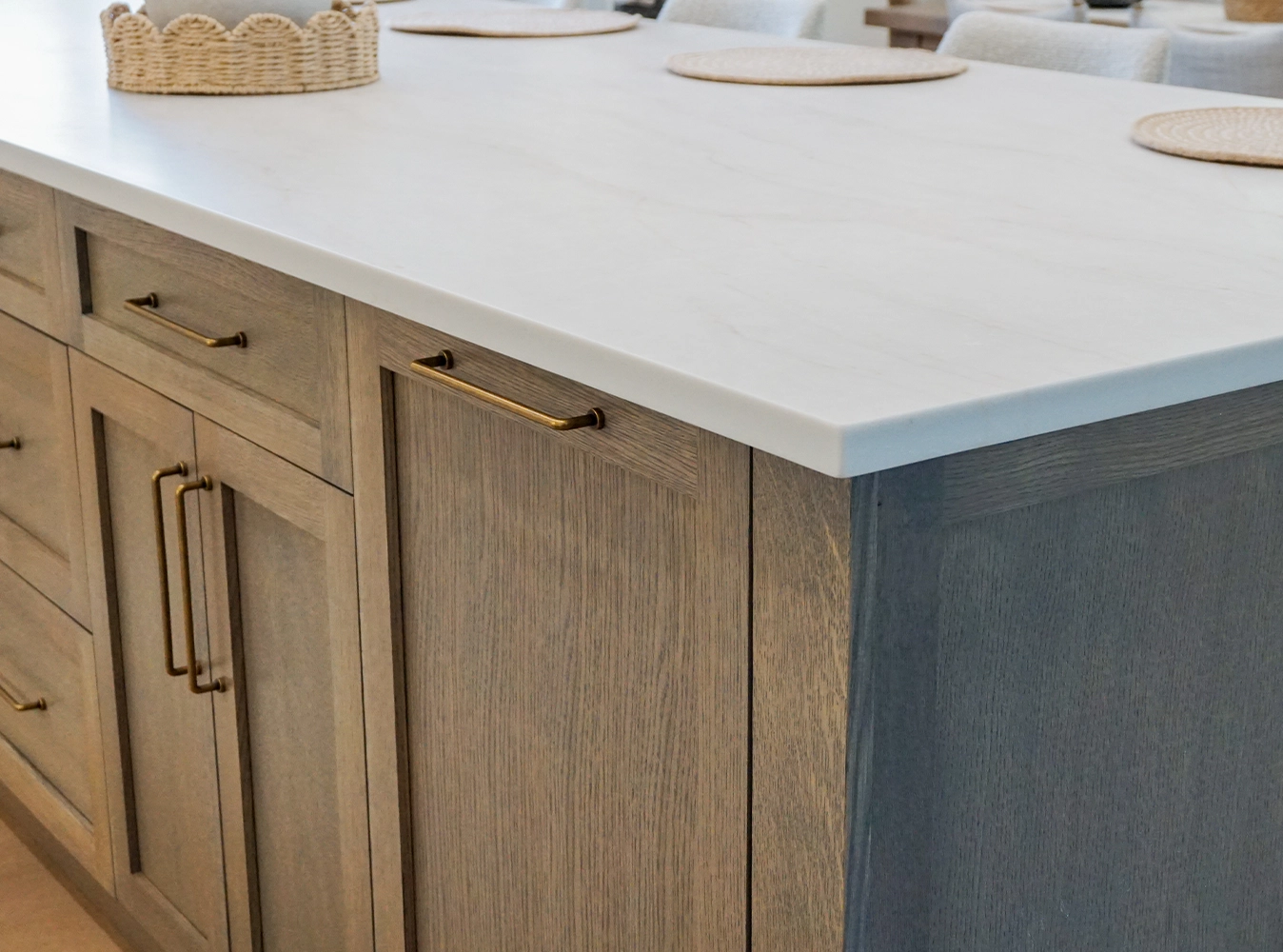 Custom oak island cabinetry with antique brass hardware and quartz waterfall countertop