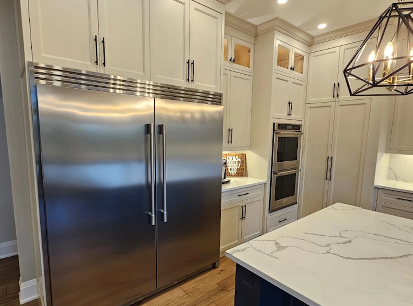 Floor-to-ceiling white shaker cabinetry with integrated appliances and glass uppers