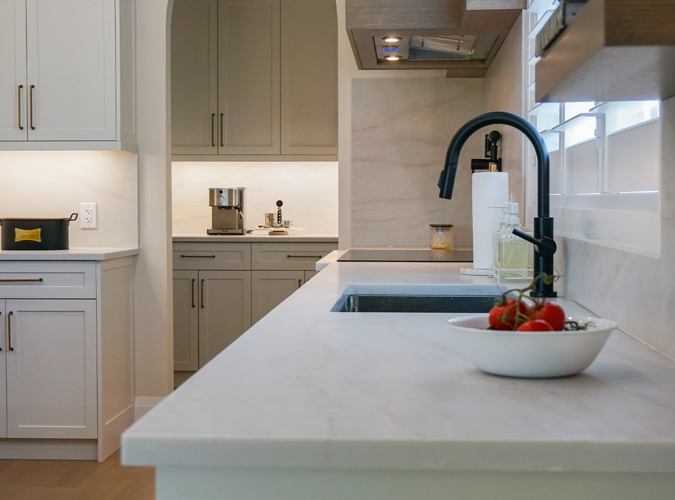 Custom kitchen with sage cabinetry, matte black faucet and marble countertops