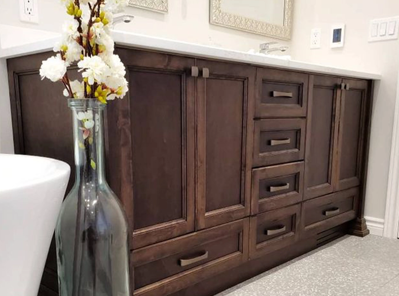 Custom dark stained wood bathroom vanity with marble countertop and freestanding tub