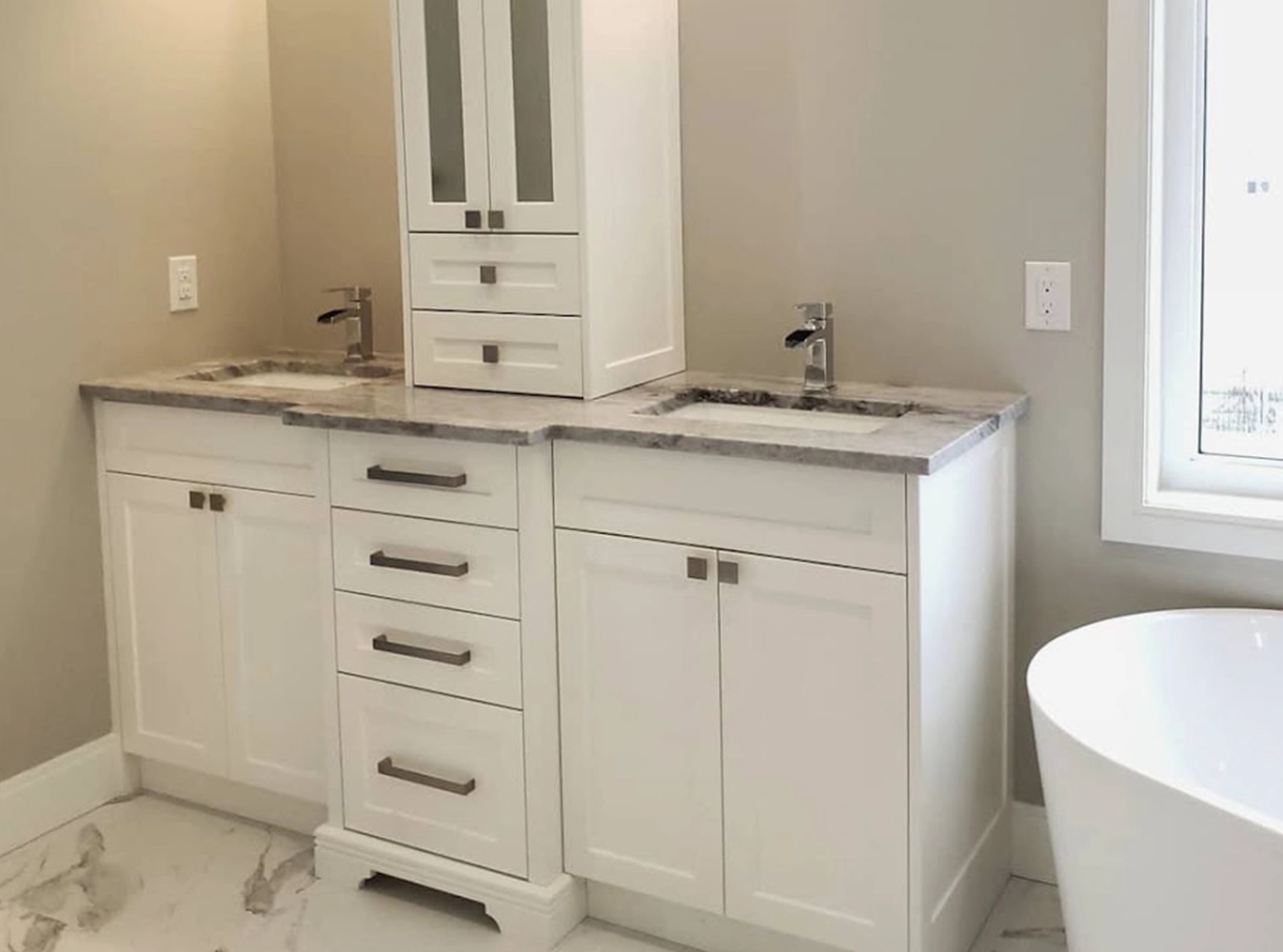 White shaker double vanity with grey marble top, linen tower and freestanding tub